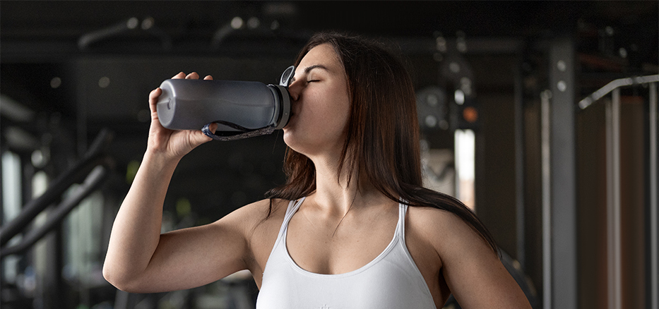 Kvinna som dricker proteinshake i ett gym