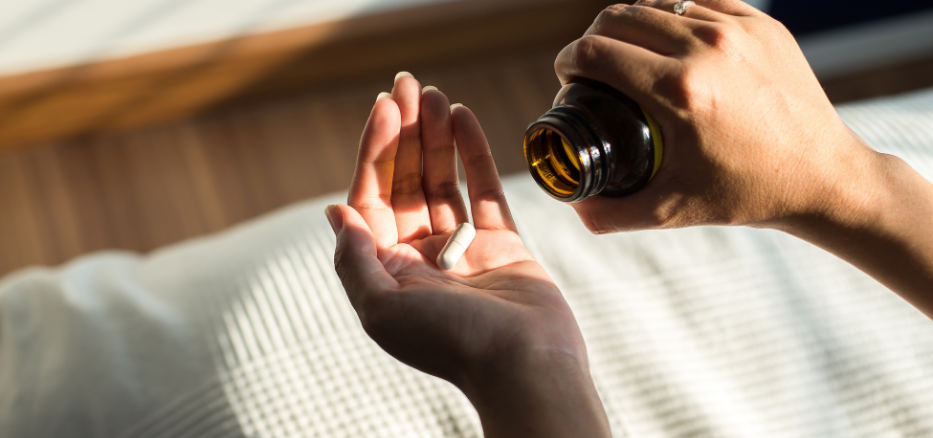 Kvinna som räcker ut handen och häller vitamintillskott på sin hand