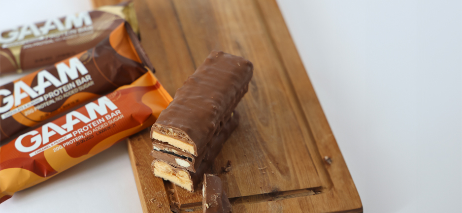 Tre proteinbars från GAAM ligger på en träplanka